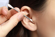 © New Africa - Woman cleaning ear with cotton swab, closeup