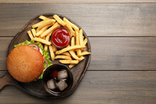 French Fries, Tasty Burger, Sauce And Drink On Wooden Table, Top View. Space For Text