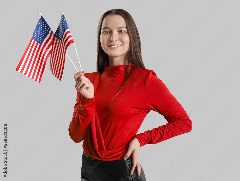 Young woman with USA flags on grey background