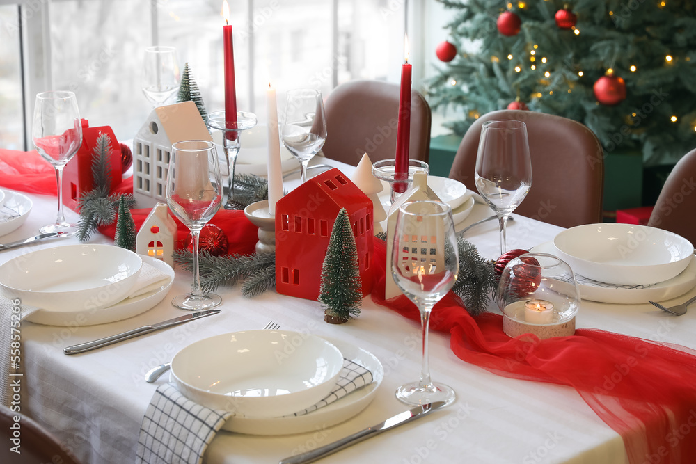 Christmas table setting with candle holders and fir branches in dining room