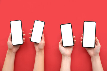Female hands with modern mobile phones on red background