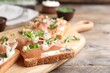 Delicious sandwiches with prosciutto, cheese and microgreens on wooden table, closeup. Space for text