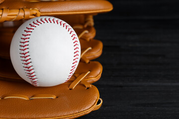 Catcher's mitt and baseball ball on black background, closeup with space for text. Sports game