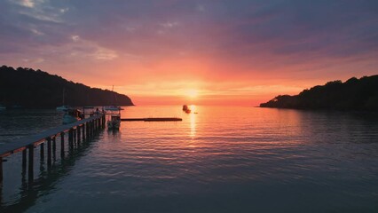 Wall Mural - Aerial view of colorful sunset over the tropical sea with wooden pier and sightseeing boat in summer