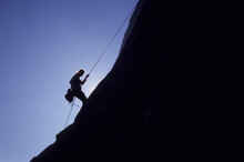 A Rock Climber Rappels Off Of A Mountain.