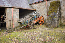 A Pair Of Old Wooden Carts Standing In An Stone Farmyard.