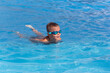 © Elena - Boy child in swimming goggles with float board tool swim in pool. Summer holiday, family vacation, water sport