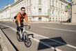 © muse studio - The concept of lifestyle, transport and people - a young man or a teenage student with a briefcase rides a bicycle on a city street in summer