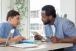© Nassorn - African American teacher and child student studying in classroom. Multiracial male tutor teaching homework lesson to boy pupil in class. Schoolboy back to school and learning with multicultural person