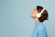 © ViDi Studio - Young happy fun caucasian woman wear knitted sweater headphones listen to music with closed eyes have fun isolated on plain pastel light blue cyan background studio portrait. People lifestyle concept.