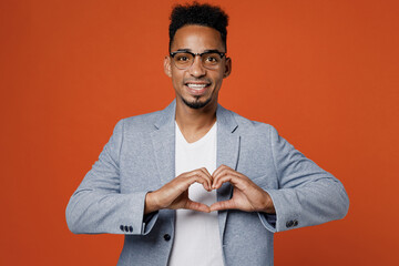 Young employee business man corporate lawyer wear classic formal grey suit shirt glasses work in office showing shape heart with hands heart-shape sign isolated on plain red orange background studio.