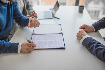 Picture of adult man, signing a clause in the contract.