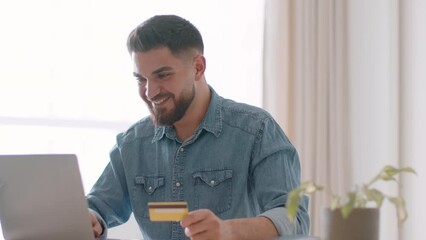 Online banking service. Young carefree arab man employee doing payment in internet, adding credit card data on website