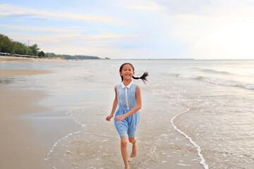 Happy Asian girl running on the sandy beach.