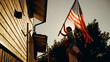 © Gorodenkoff - Cinematic Shot of a Father Holding His Small Daughter of His Shoulders, Helping Her to Raise the United States of America Flag to Celebrate a National Fourth of July Holiday at Their House.