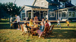 © Gorodenkoff - Parents, Children and Friends Gathered at a Barbecue Dinner Table Outside a Beautiful Home. Old and Young People Have Fun, Eat and Drink. Garden Party Celebration in a Backyard.