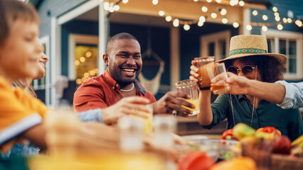 Family and Multiethnic Diverse Friends Gathering Together at a Garden Table Dinner. Old and Young People Toasting and Clinking Glasses with Fresh Orange Juice and Celebrating an Event.