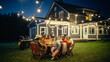 © Gorodenkoff - Parents, Children and Friends Gathered at a Barbecue Dinner Table Outside a Beautiful Home with Lights Decorations. Old and Young People Have Fun and Eat Food. Garden Party Celebration in a Backyard.