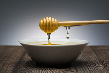 Wall Mural - honey drips from the spoon into a white bowl