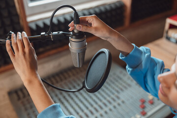 Wall Mural - Close-up of audio engineer working in sound record studio, using microphone, mixing board, software to create new song