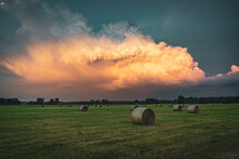 Thunderclouds Streaked By Sun Over Hay Bales Over Field