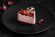 Heart Cake Decorated With Pomegranate And Strawberries. Dessert On A Black Plate With Dried Rose.