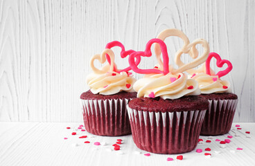 Aufkleber - Valentines Day theme red velvet cupcakes with sweet hearts and white icing. Side view with a white wood background.
