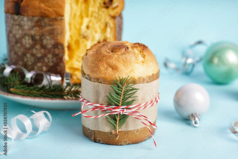 Tasty Panettone with Christmas decor on blue background, closeup