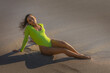 © bartsadowski - Woman in neon green swimsuit sitting on the beach