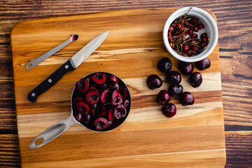 Canvas Print - Halved and Pitted Cherries on a Wood Cutting Board: Raw cherries with tools to slice and pit them viewed from above