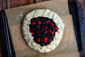 Wall Mural - Unbaked Mixed Berry Galette on a Parchment-Lined Sheet Pan: Rustic dessert tart made with raspberries, blueberries, and blackberries