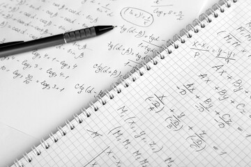 Paper with different mathematical formulas and pen, closeup