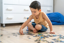 Child Playing Puzzles At Home. Little Child Holding Puzzle Pieces And Trying To Solve It.