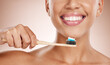 © C Davids/peopleimages.com - Woman, cosmetics and brushing teeth for dental hygiene, smile and clean mouth on studio background. Female, girl and tooth brush for oral health, healthcare and fresh breath for natural care or relax