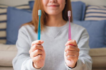 Wall Mural - Closeup image of a young woman holding and showing two toothbrush