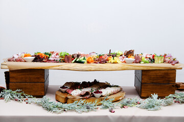 Buffet table with cold appetizers. Meat and vegetable snacks are placed on wooden stands