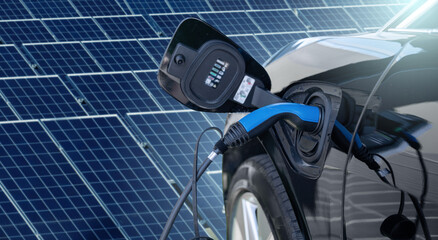 Sticker - Close up of electric car with a connected charging cable on the background of solar panels	