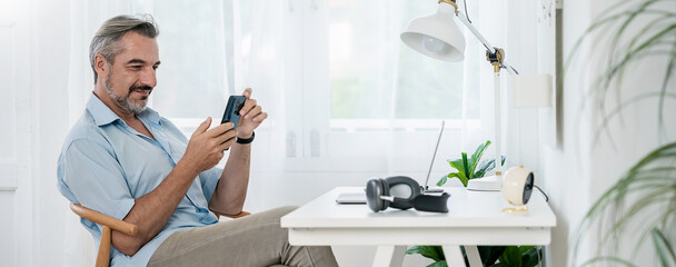 Portrait of happy caucasian business senior man casual cloths shirt work in home office desk using phone computer. Small business employee freelance online sme marketing e-commerce telemarket