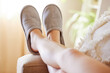 Legs, relax and woman in slippers on sofa resting on weekend at home. Shoes, freedom and female relaxing, lying and spending time alone on comfy, cozy and comfortable couch in living room of house.