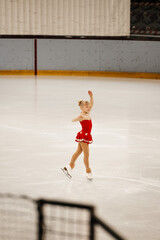 Wall Mural - a little girl in a red dress participates in a figure skating competition	