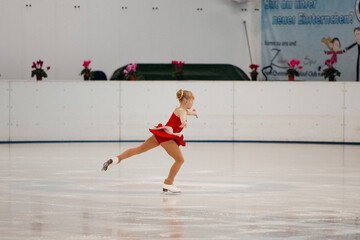 Wall Mural - a little girl in a red dress participates in a figure skating competition	