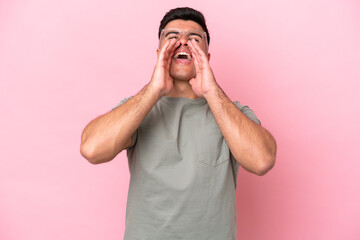 Wall Mural - Young caucasian handsome man isolated on pink background shouting and announcing something