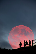 Silhouette Of People In Front Of The Red Moon In Inverness, Scotland.