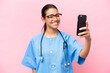 Young nurse Colombian woman isolated on pink background making a selfie
