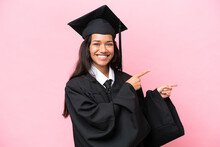 Young University Colombian Woman Graduate Isolated On Pink Background Pointing Finger To The Side And Presenting A Product