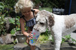 © Cavan Images - young girl helping her dog get water from drinking cup in summertime