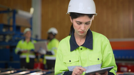 Female engineer using tablet at modern factory. She checking and maintenance machine in factory.