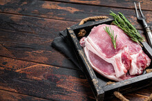 Ready For Cooking Raw Pork Chop Steaks In A Wooden Tray With Rosemary. Wooden Background. Top View. Copy Space