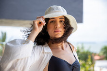 Woman At Beach House Wearing Hat And Looking At Camera, Hair In The Wind