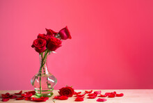 Red Roses In Glass Vase On Red Background